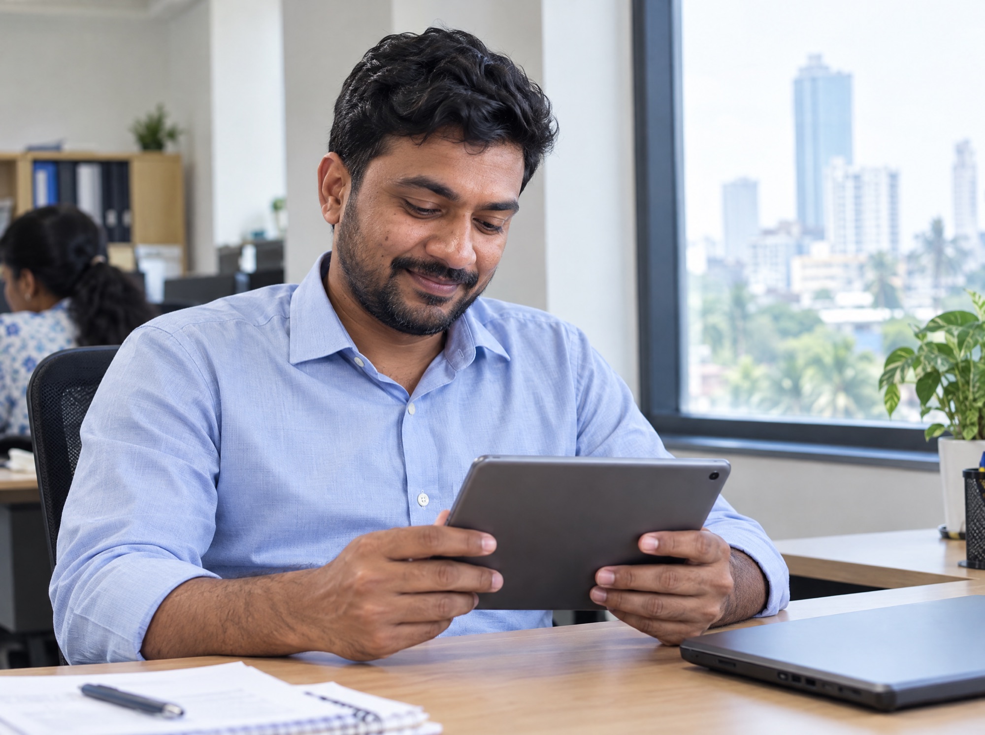 Laundry owner checking his shop on a tablet at his office desk